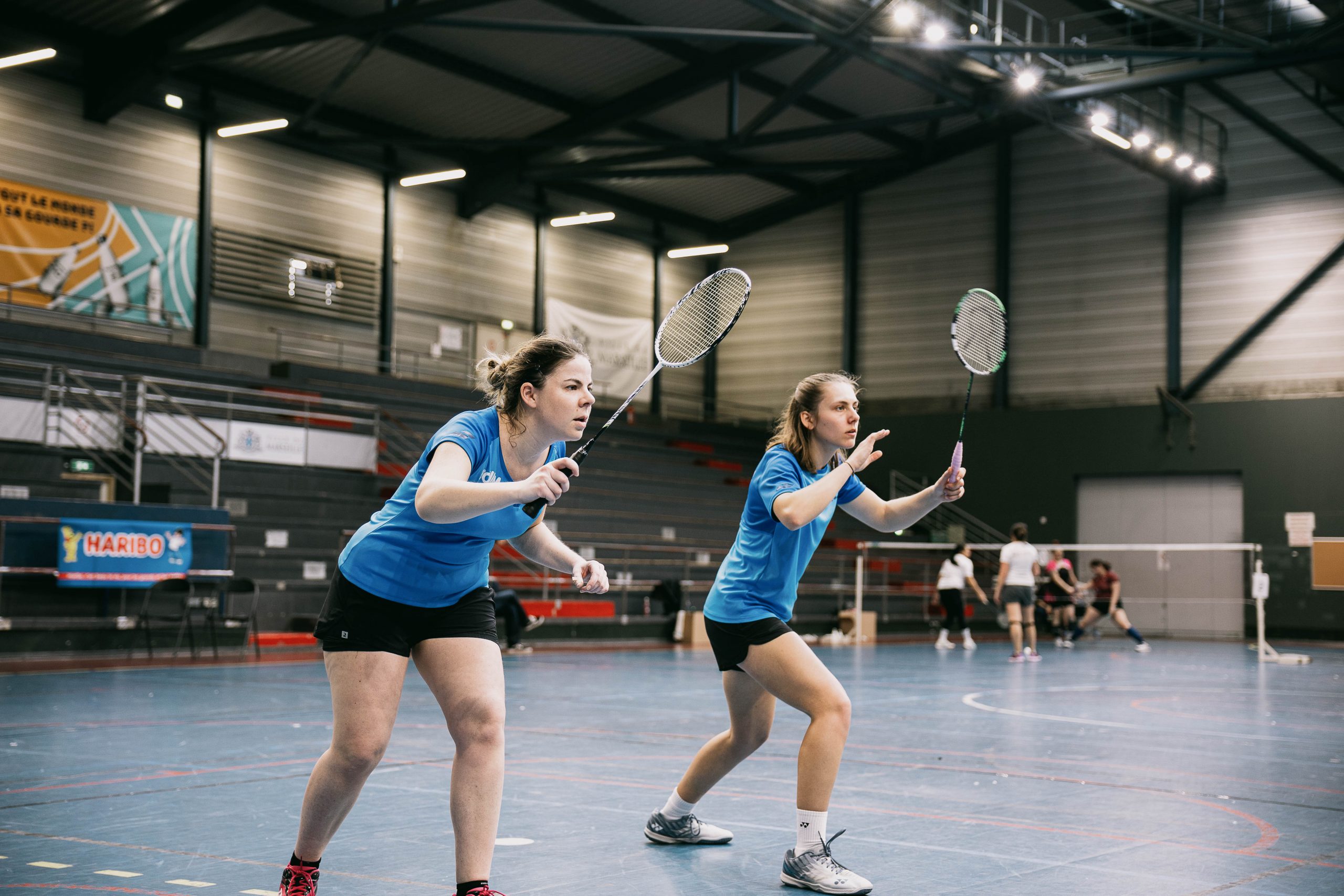 Deux femmes qui s'apprêtent à recevoir un service au badminton.